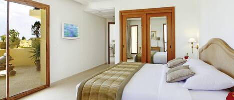 Habitación de hotel con cama, mesita de noche, lámpara, un cuadro y vistas a través de una puerta de cristal.