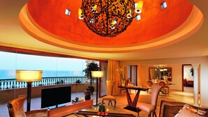 Un espacio habitable amplio con una televisión grande, asientos cómodos, una mesa de comedor y vistas al mar.