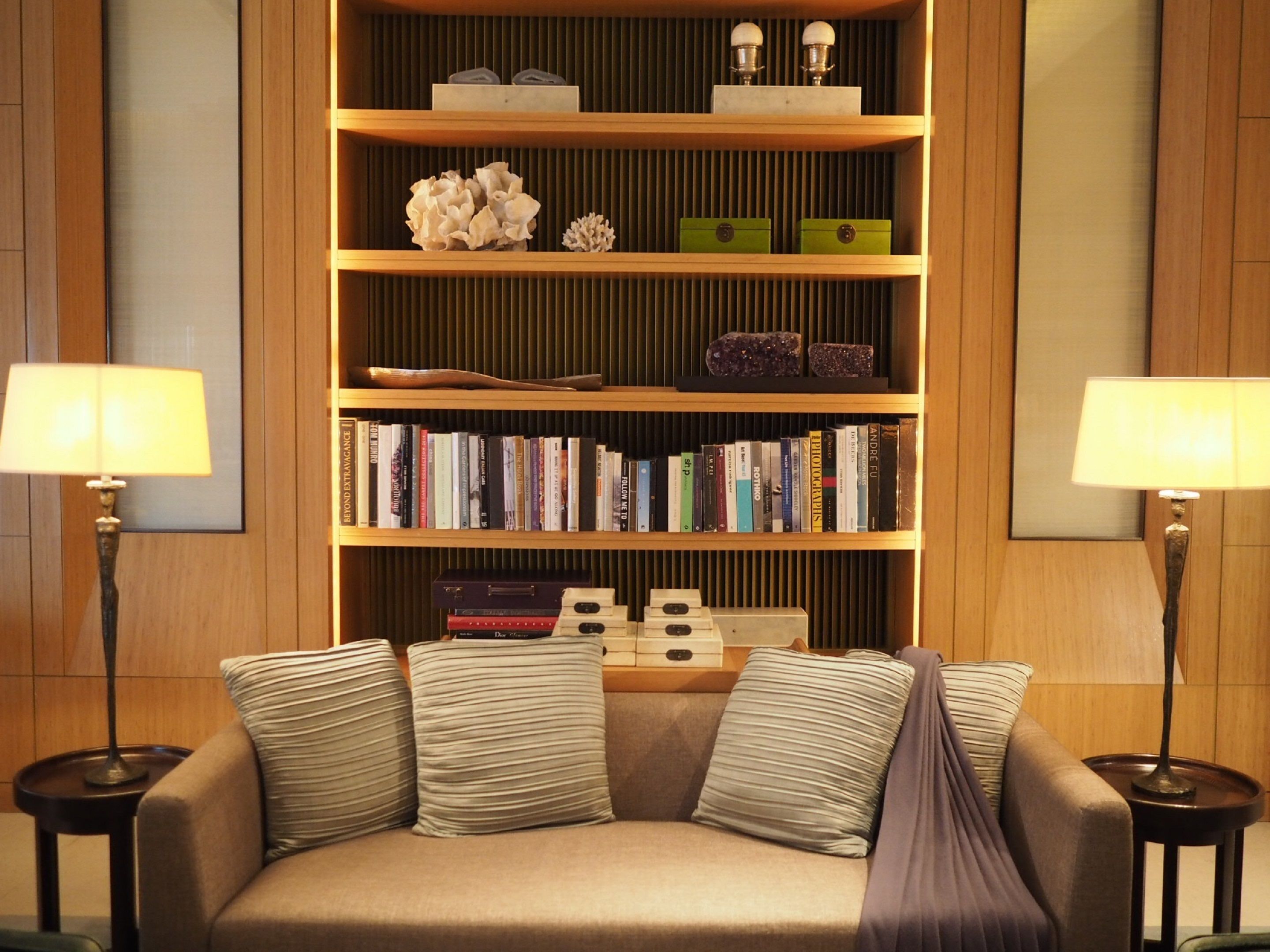 A cozy reading area with a sofa, bookshelves, and two lamps.