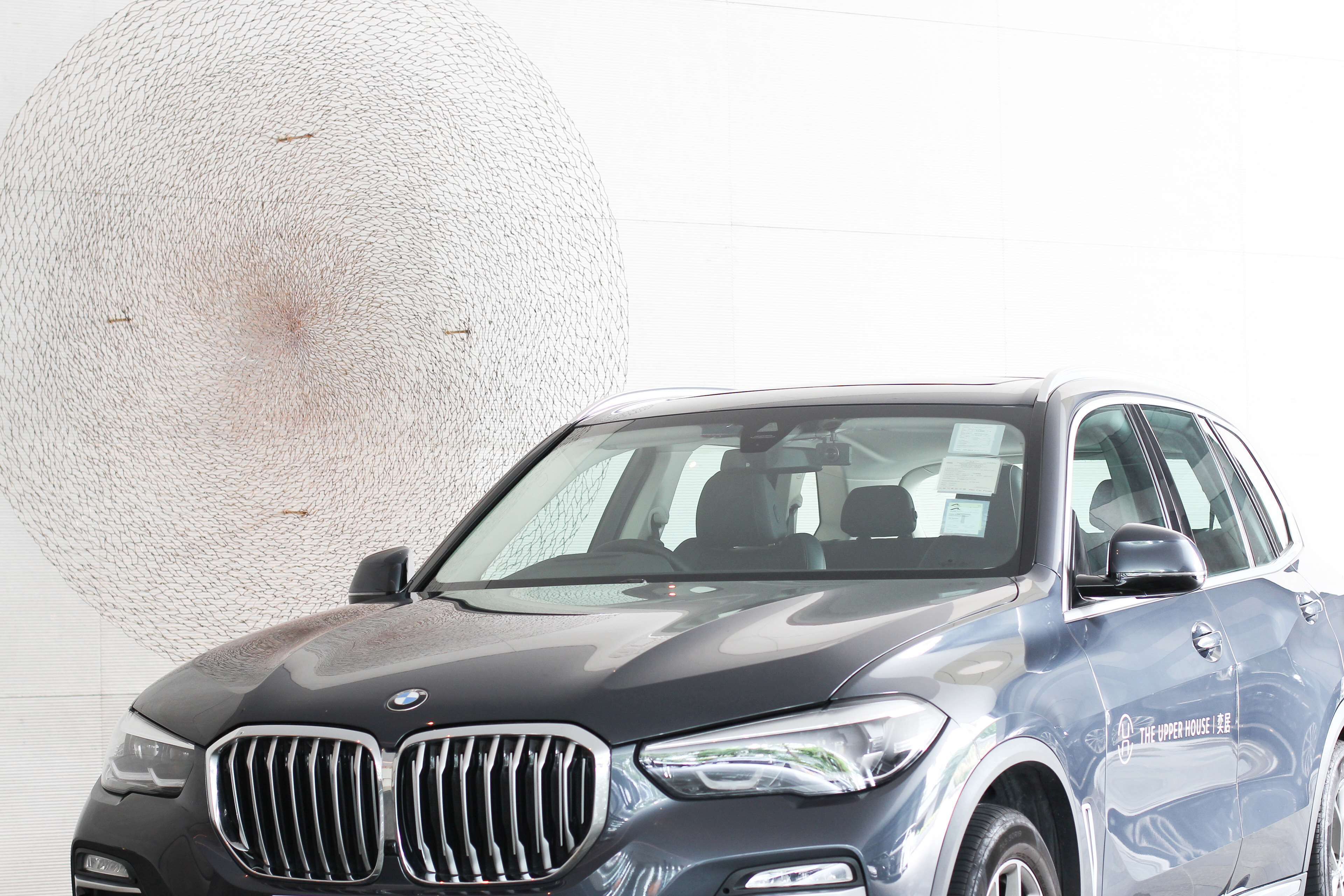 A BMW SUV with a visible logo and text on the side, parked in front of a large spherical object.