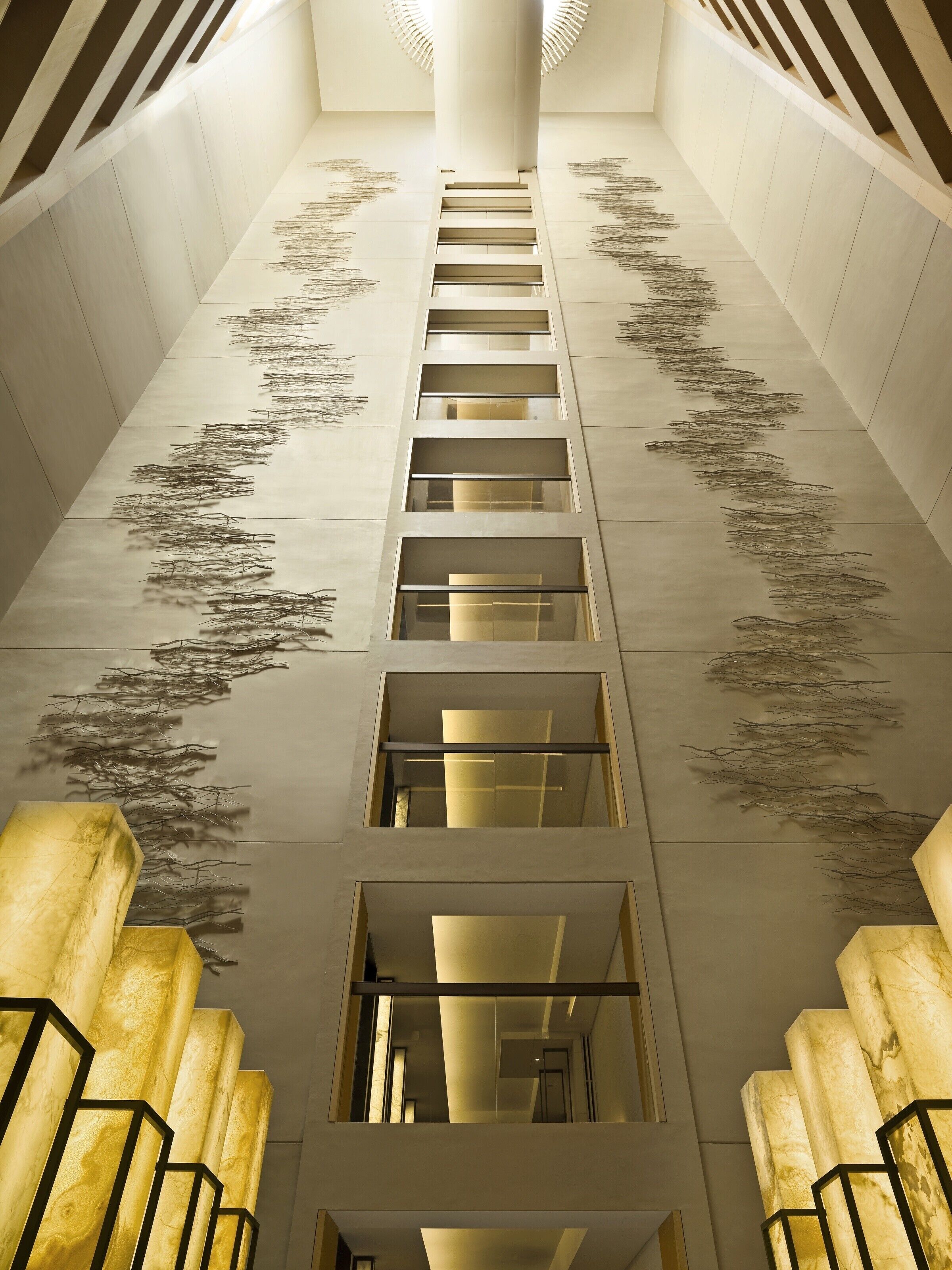 A modern interior with a central staircase, glass railings, and a patterned floor design.