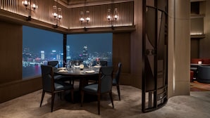 Un espace repas offrant une vue sur la ville, doté d’un mobilier moderne et d’un éclairage d’ambiance.
