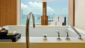 Une salle de bain moderne dotée d’une grande fenêtre, d’une baignoire, d’un lavabo avec plusieurs robinets et d’un mur d’accent en bois.