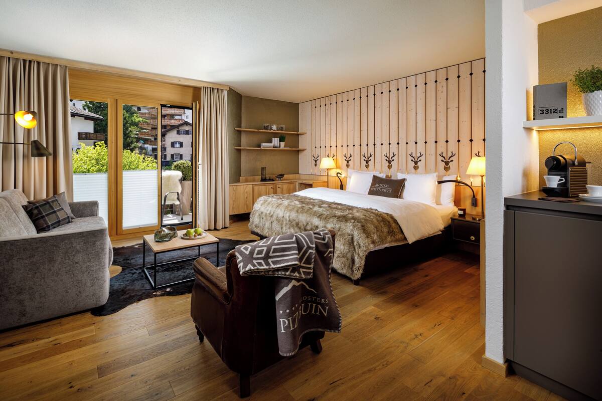 Habitación de hotel moderna con una cama grande, un sofá, un escritorio y vistas al exterior.