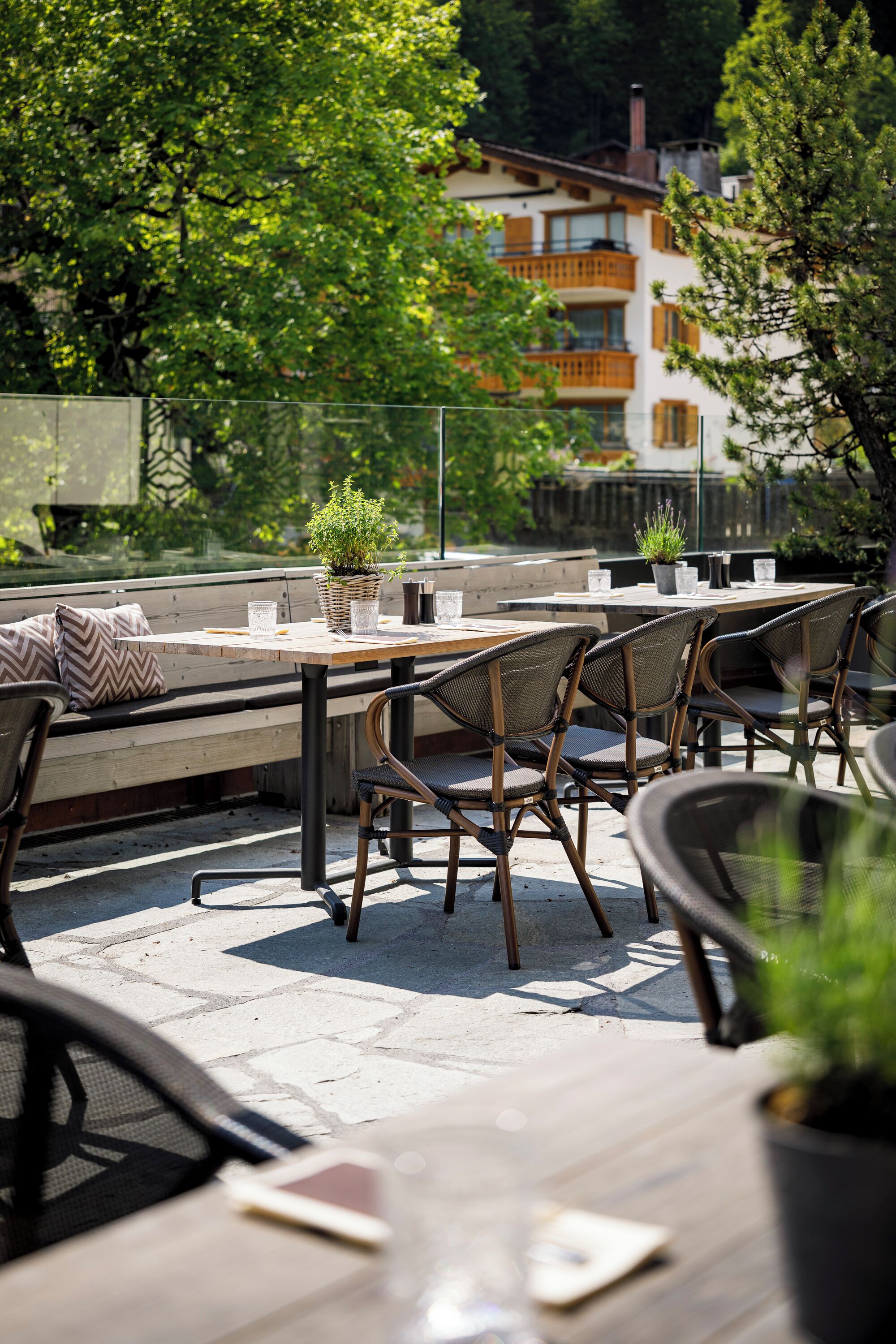 An outdoor patio with tables and chairs, a bench, and potted plants.