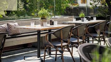 An outdoor patio with tables and chairs, a bench, and potted plants.