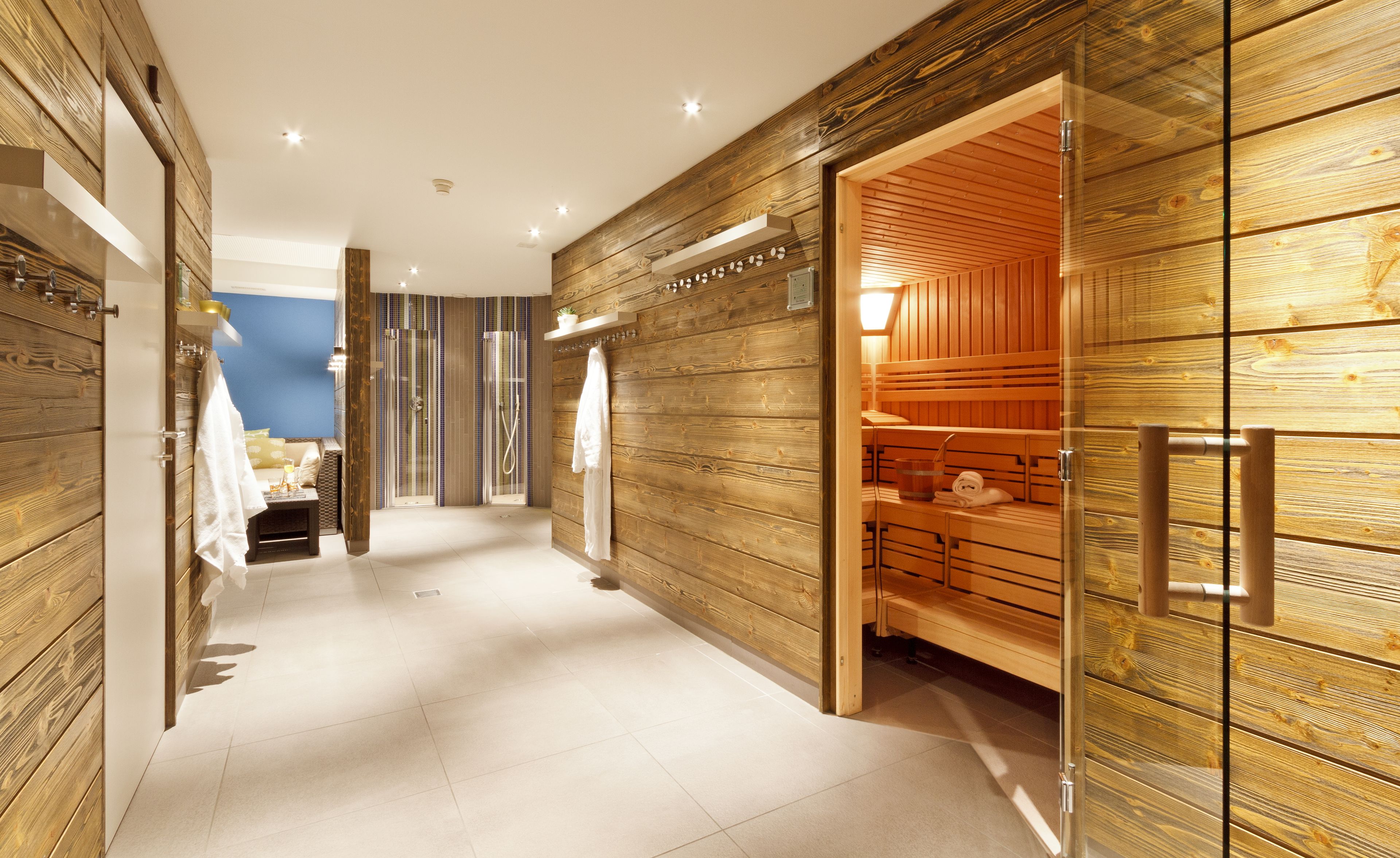 A modern spa area with wooden paneling, a sauna, and a glass-enclosed shower area.