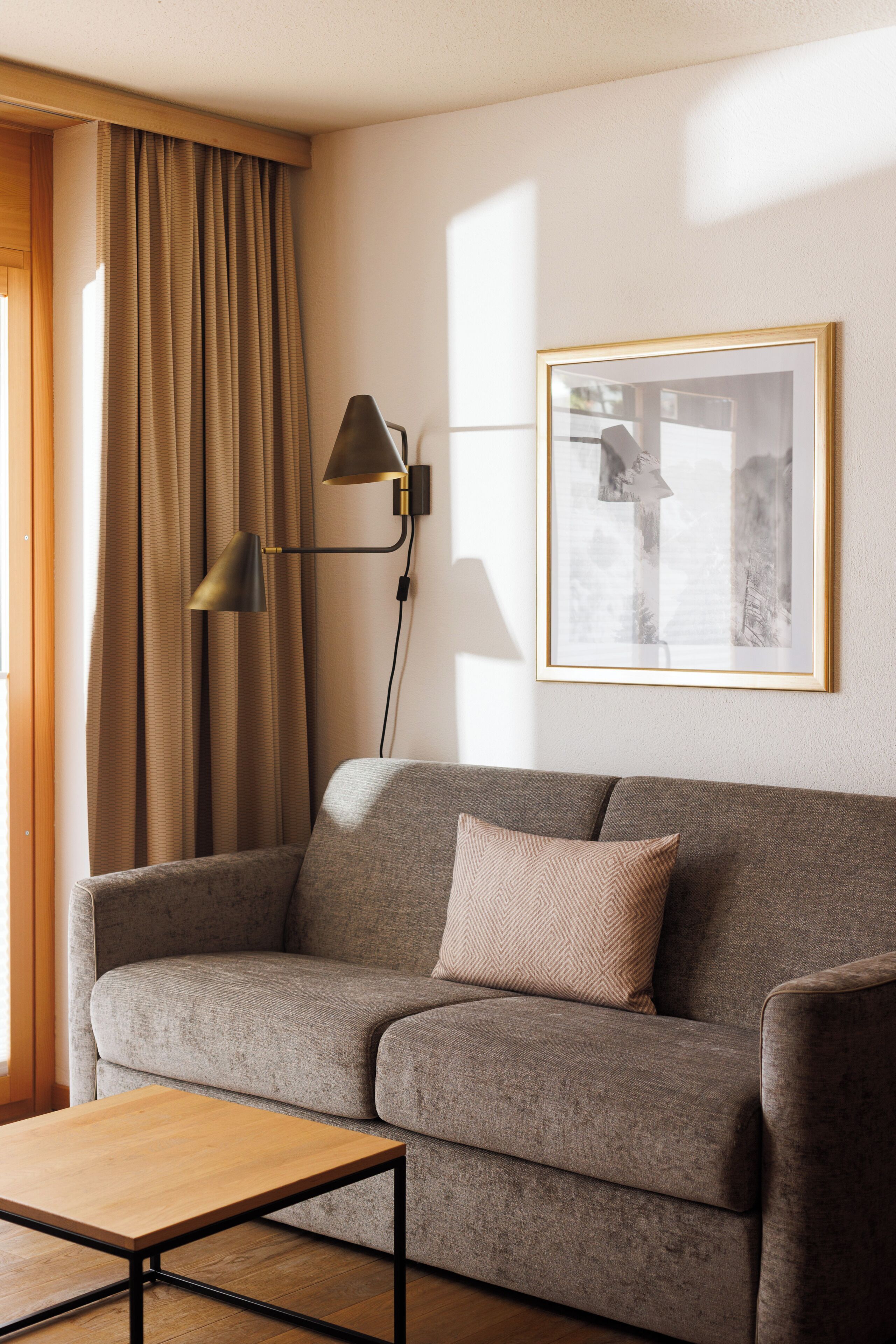 Una sala de estar con un sofá, una mesa, una lámpara, un marco de fotos y una ventana con cortinas.