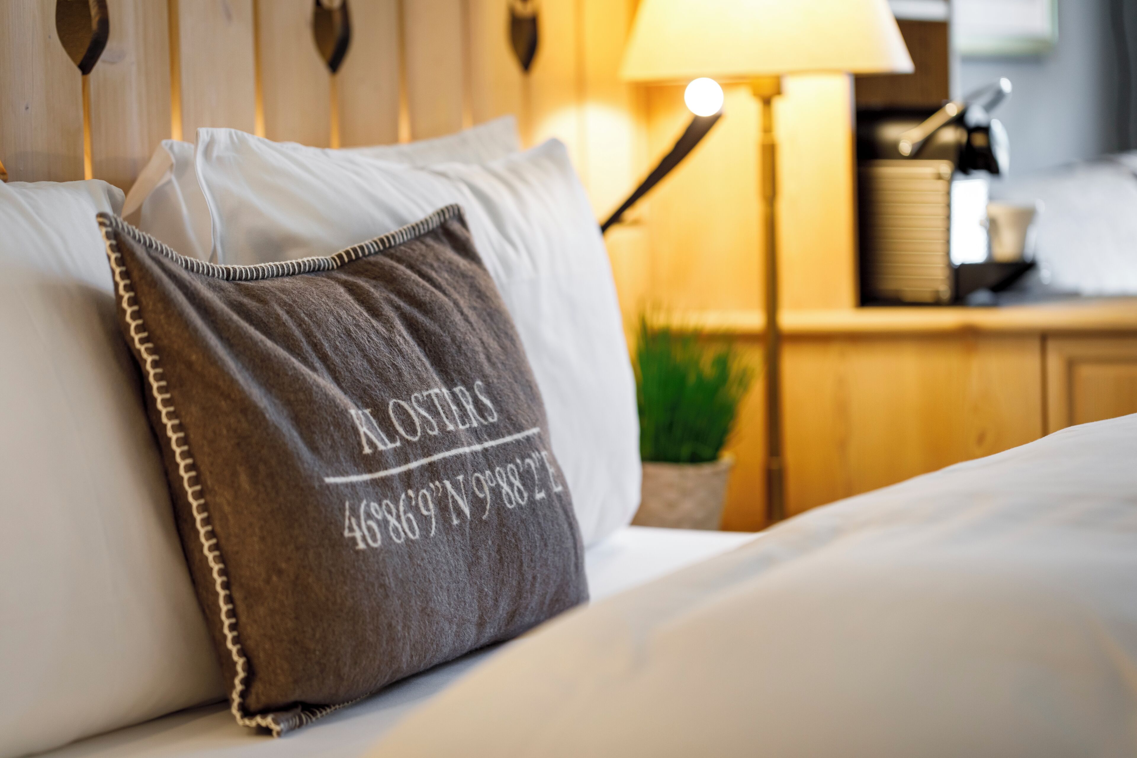 Una cama bien hecha con un almohada que tiene coordenadas impresas.