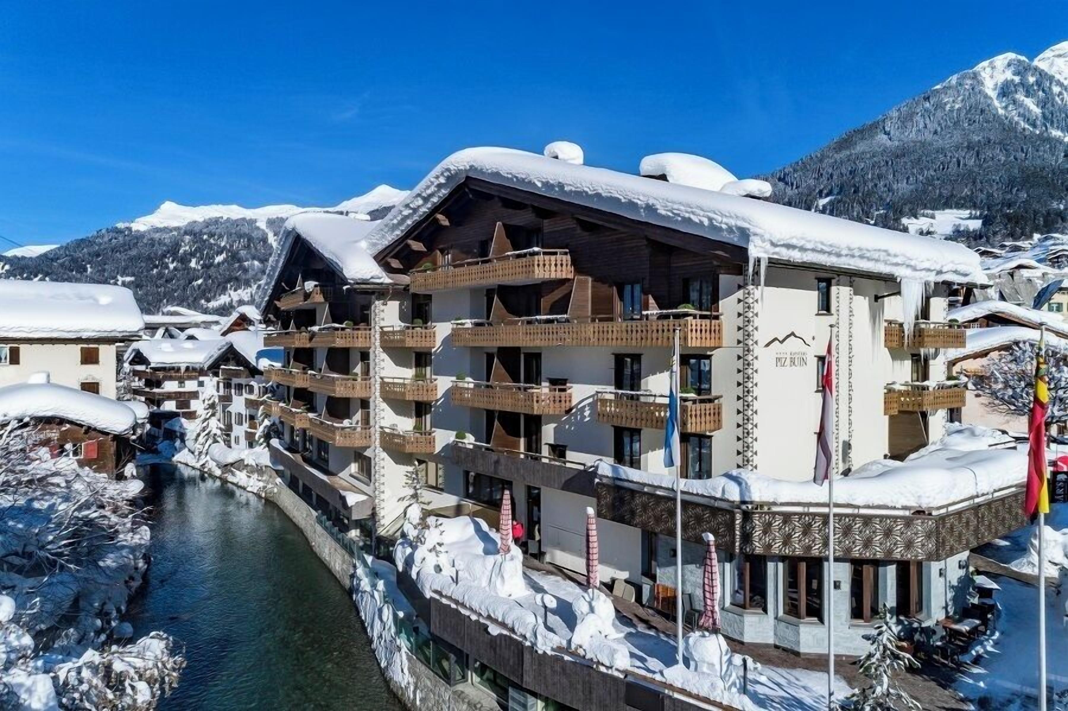 A multi-story hotel with balconies and a river in the foreground.