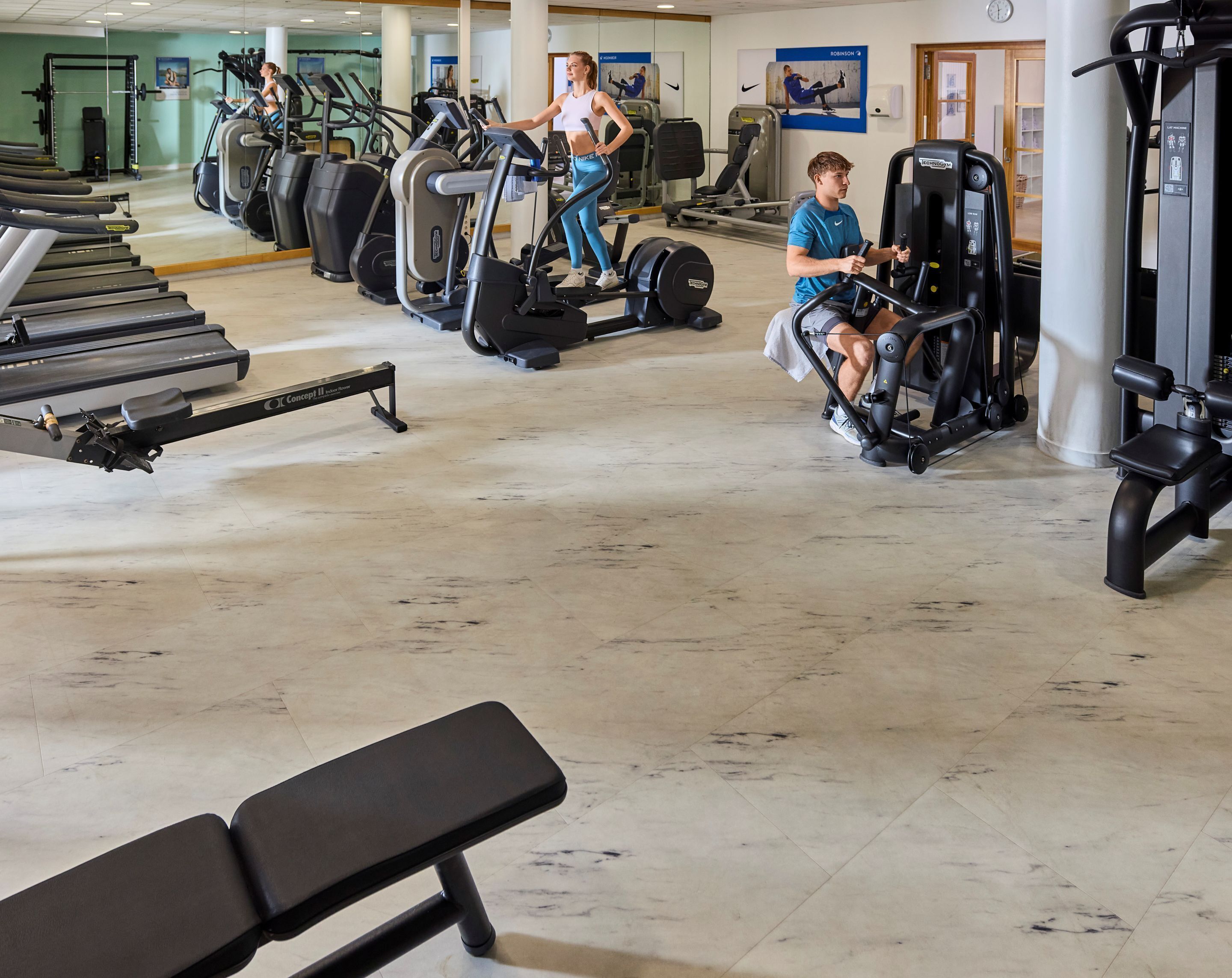 Ein Fitnessstudio mit Laufbändern, Crosstrainern und Rudergeräten.