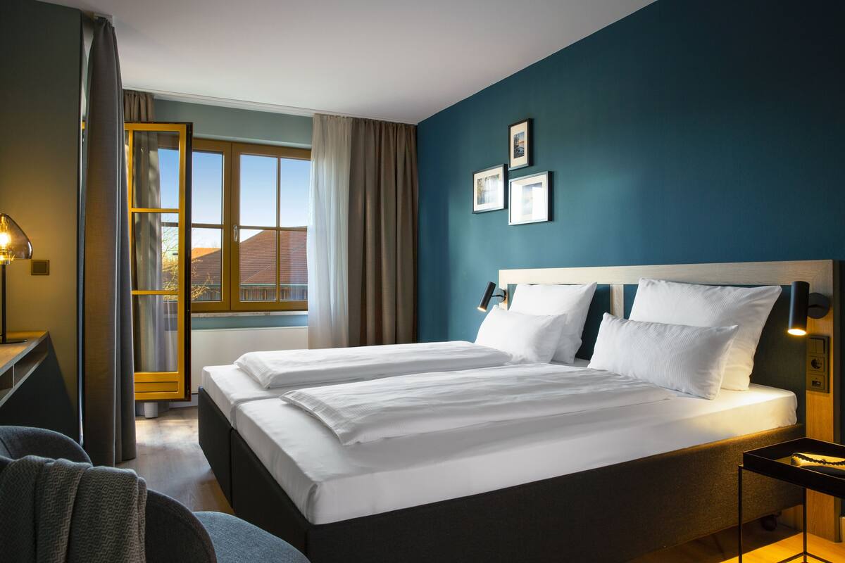 A hotel room with a large bed, a desk, and a window with curtains.