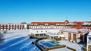 Et hotel med swimmingpool, flere bygninger og en klar blå himmel.