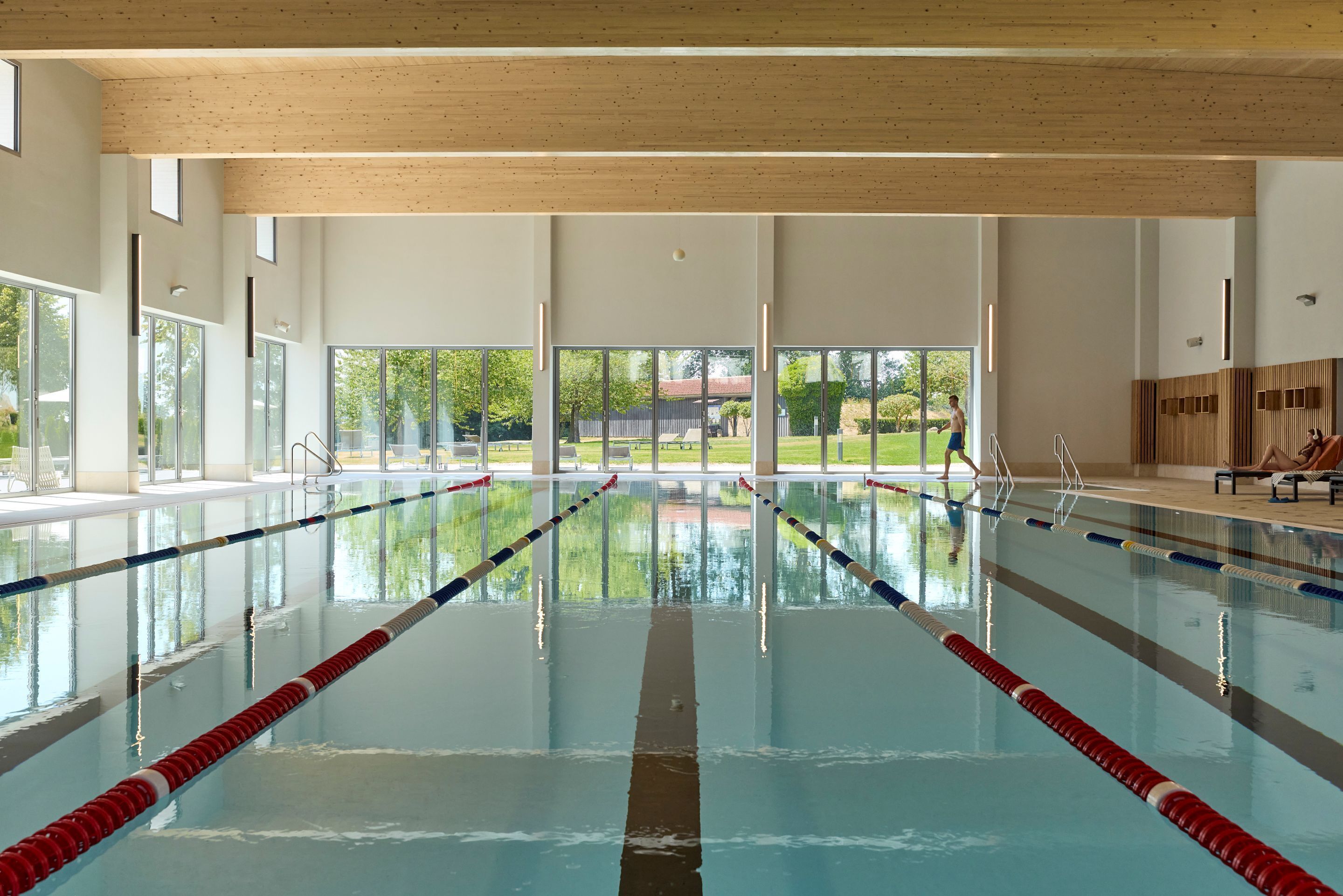 En indendørs swimmingpool med tydelige baner, store vinduer og udsigt til det fri.