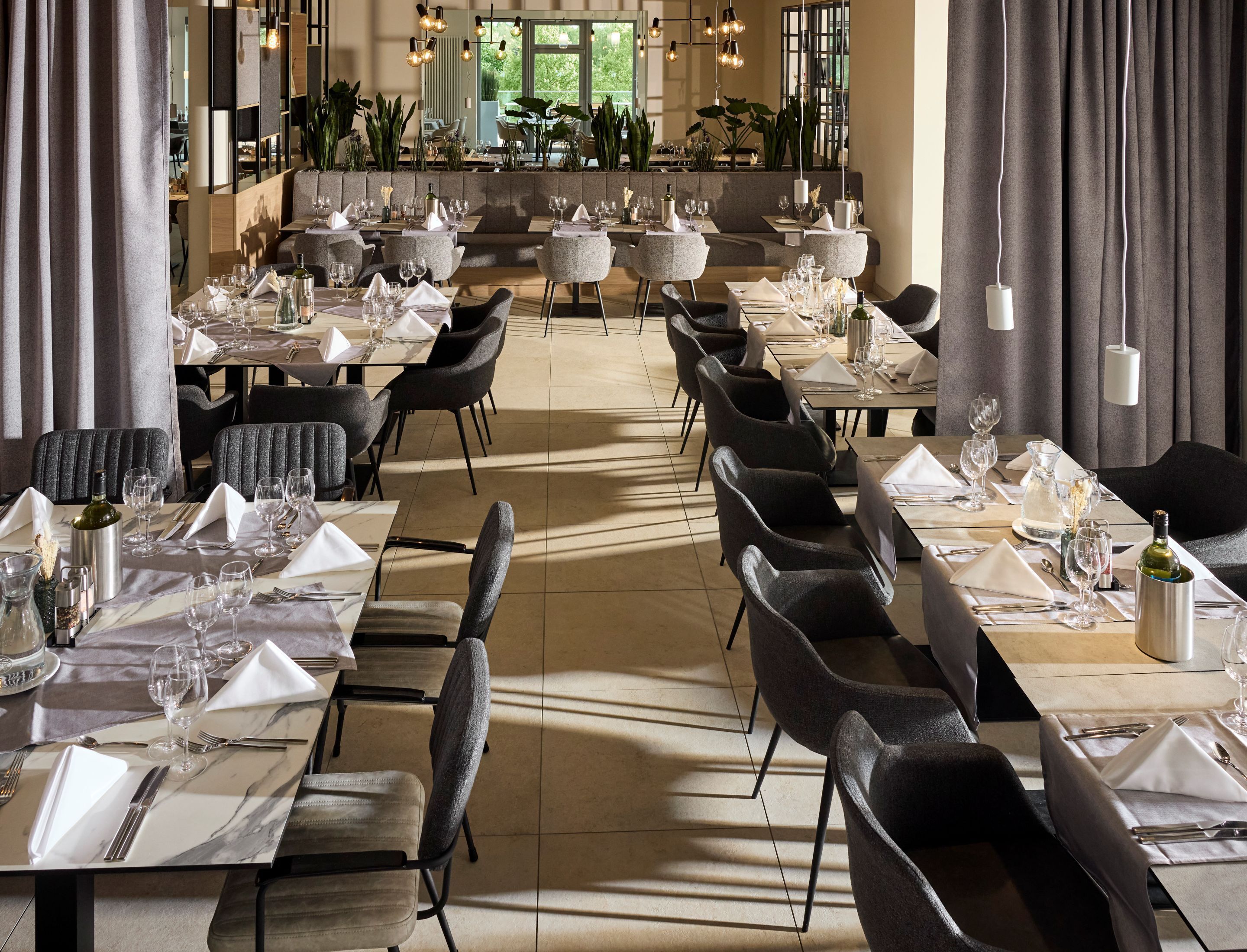 En rummelig restaurant med flere borde og stole, indrettet i et moderne design med udsigt til det fri.