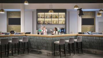 A modern bar area with a bar counter, stools, and a well-stocked shelf of liquor bottles.