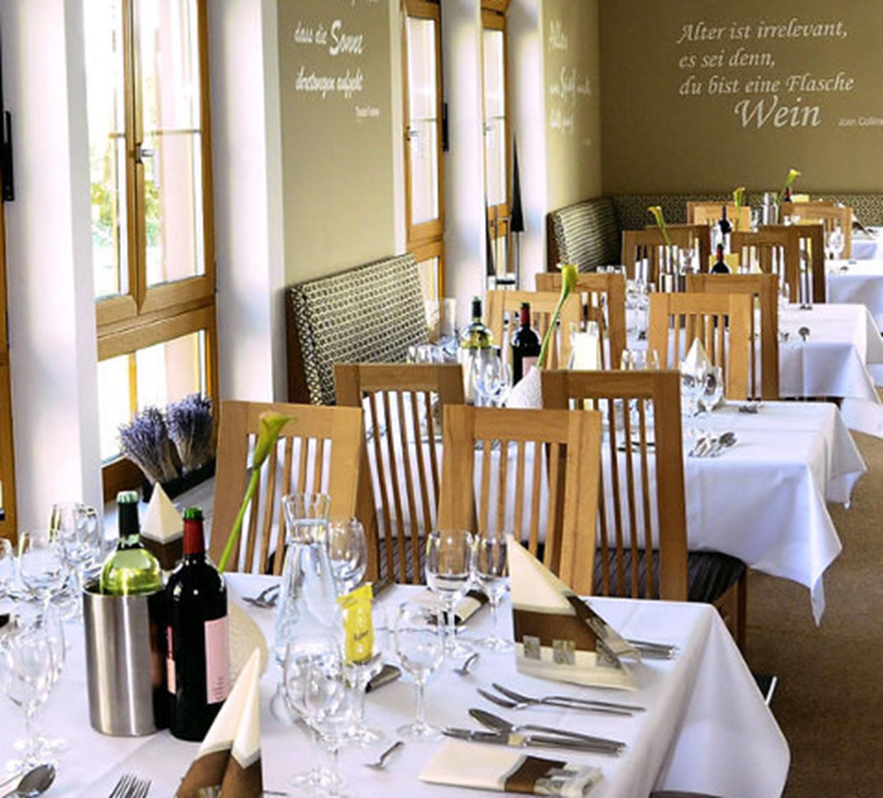 Un restaurante con mesas dispuestas para comer, con vistas a la ciudad a través de amplios ventanales.