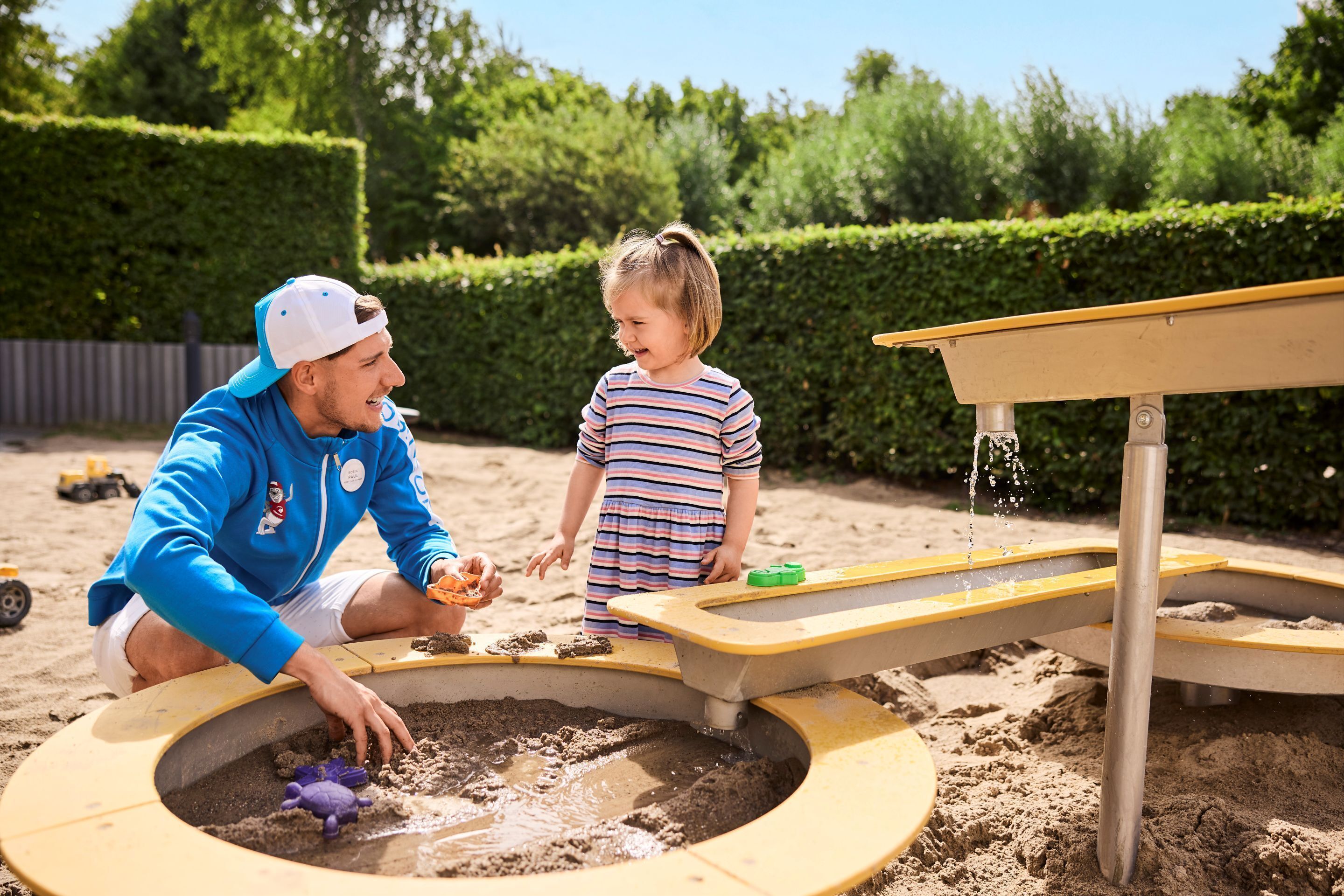 A sandy play area with a circular sandbox and a small table.