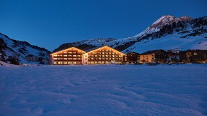 Un grand hôtel illuminé, avec de nombreux étages, et une montagne imposante en arrière-plan.