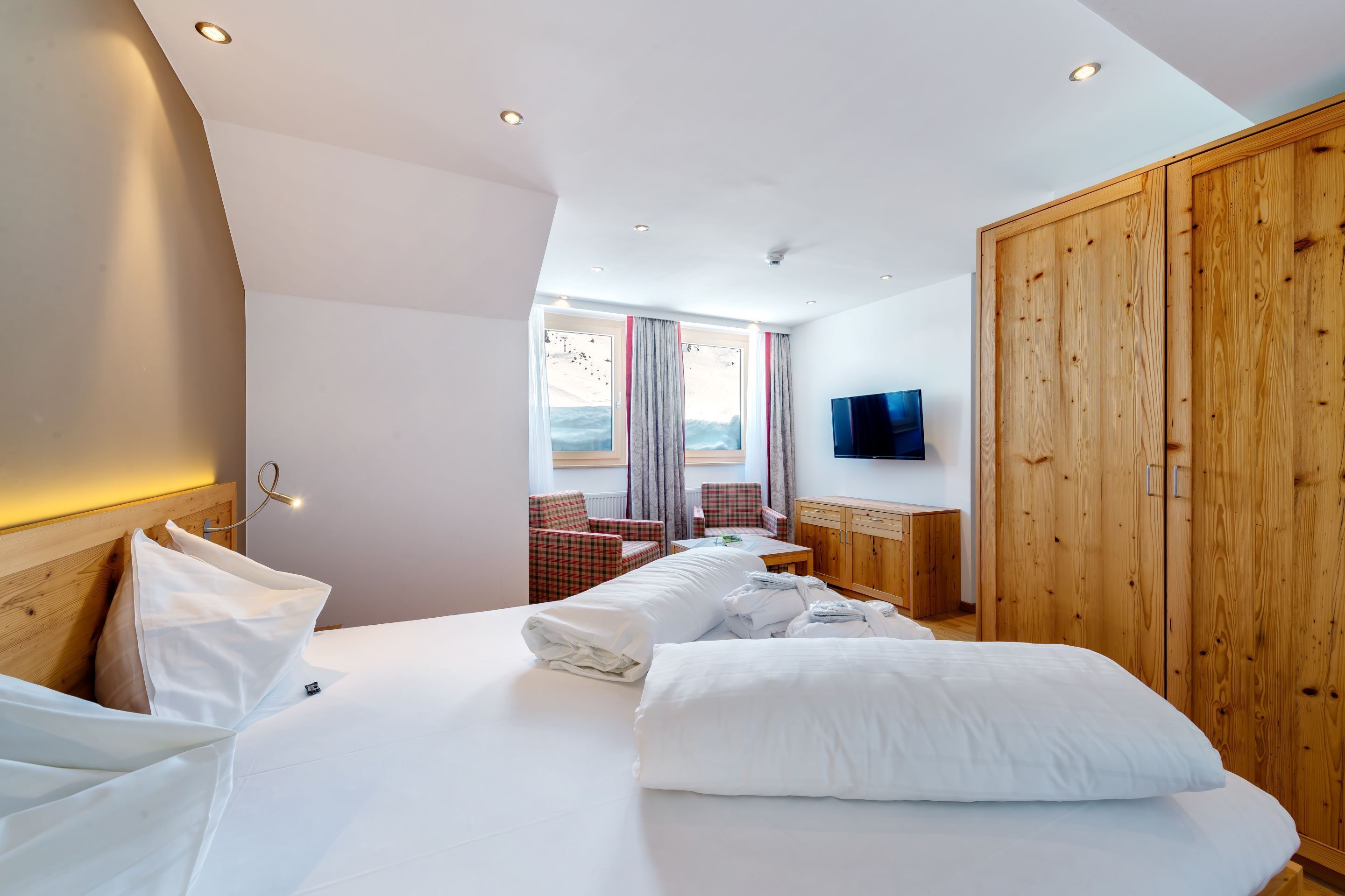 Une chambre d’hôtel moderne dotée d’un grand lit, d’une armoire en bois, d’une télévision et offrant une vue sur l’extérieur.