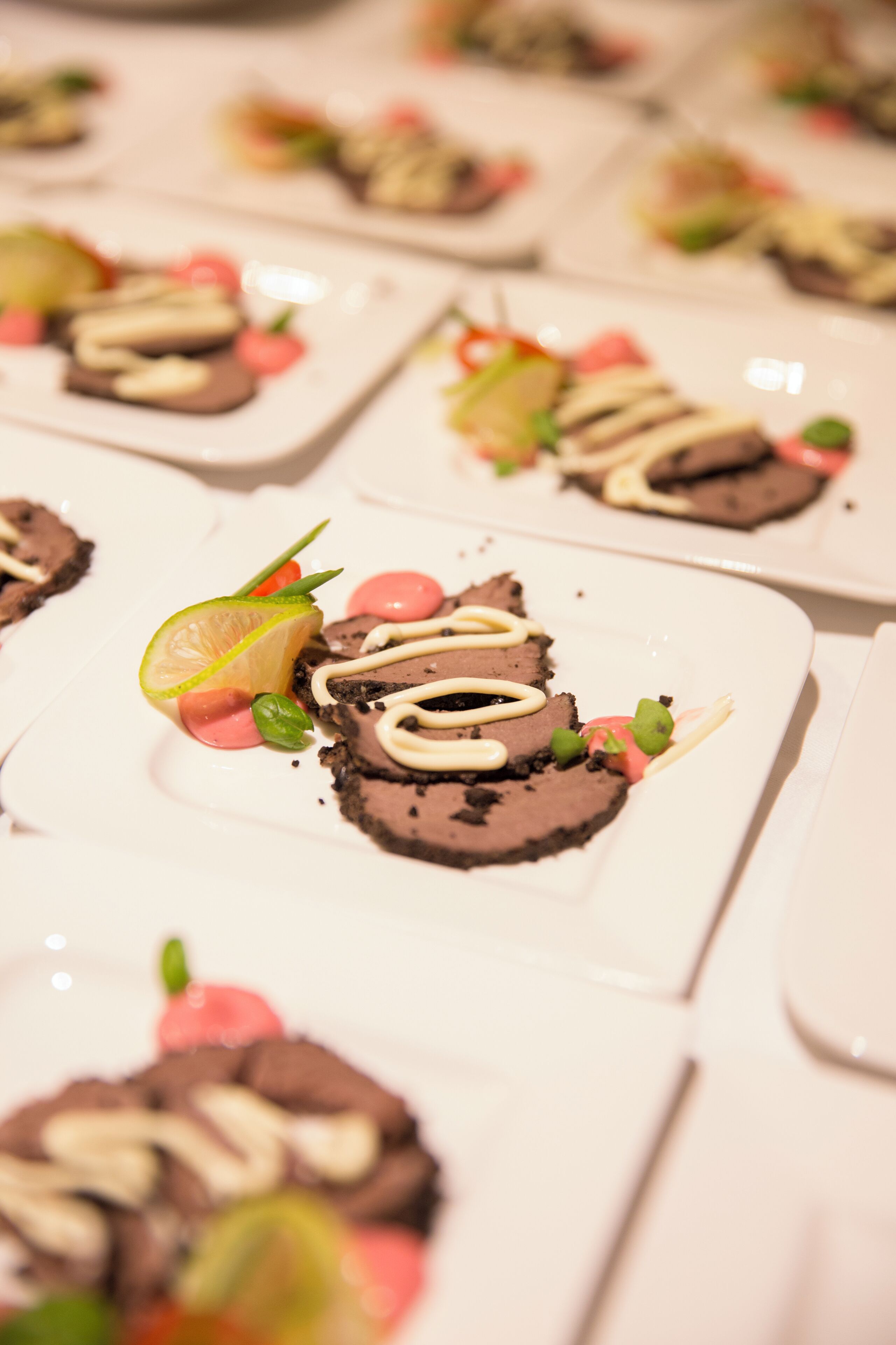 A series of square plates with chocolate mousse and garnishes.