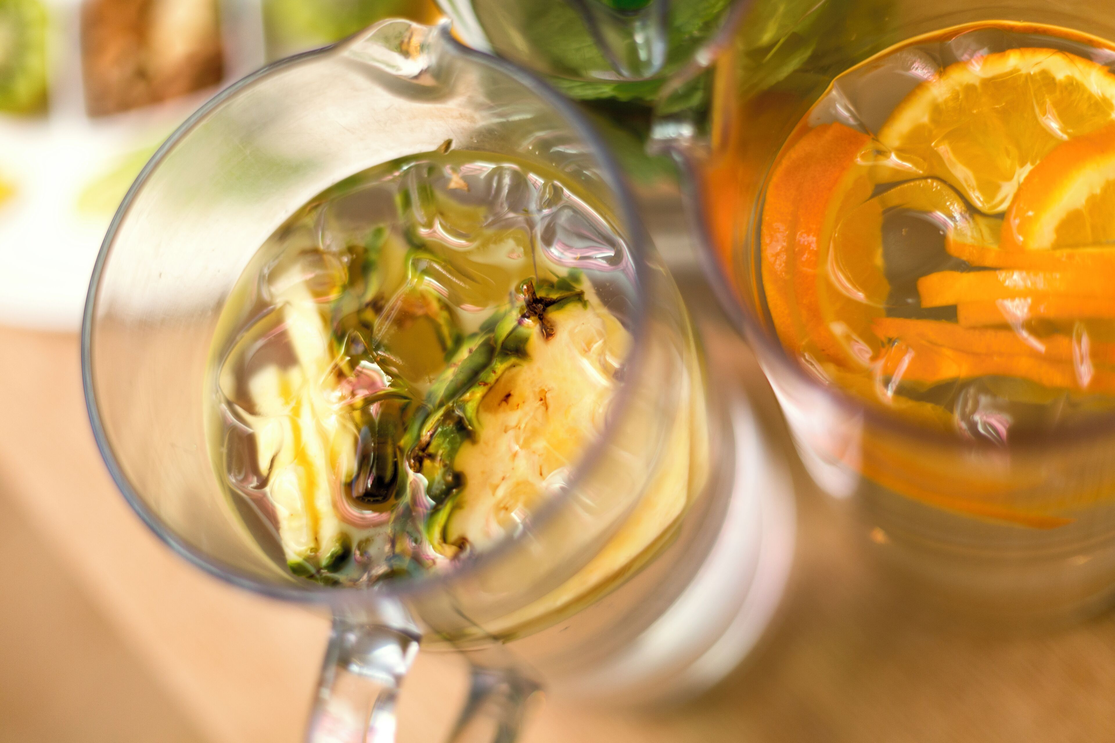Two glasses of tea with slices of orange and mint leaves.
