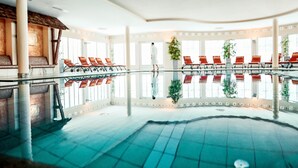 Une piscine intérieure avec des chaises rouges et une personne qui se promène.