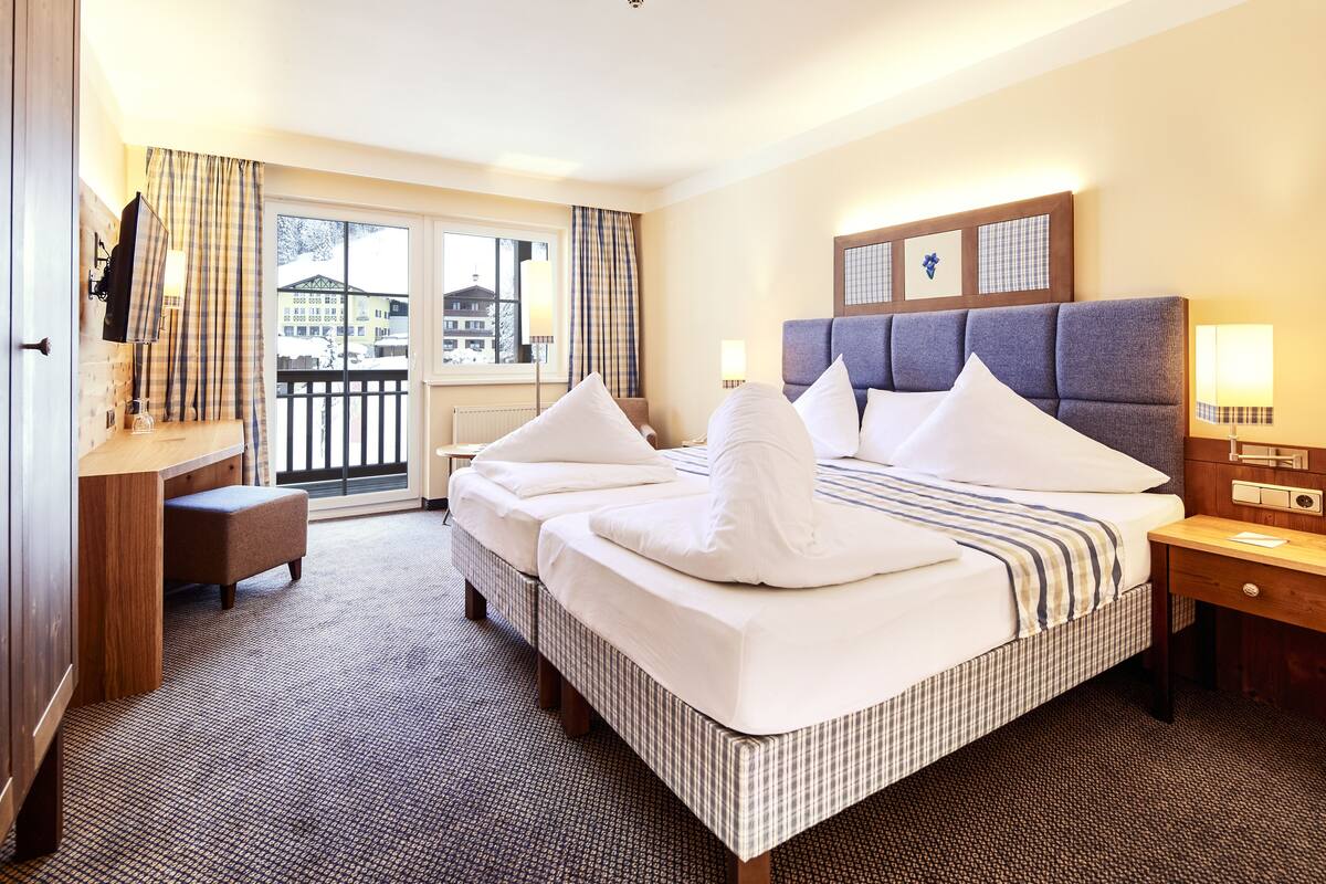 Habitación de hotel con una cama grande, un escritorio, una silla y vistas al exterior.