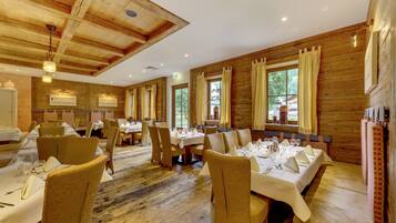 Ein Restaurant mit Holzwänden und -decken, gedeckten Tischen und Blick ins Freie.