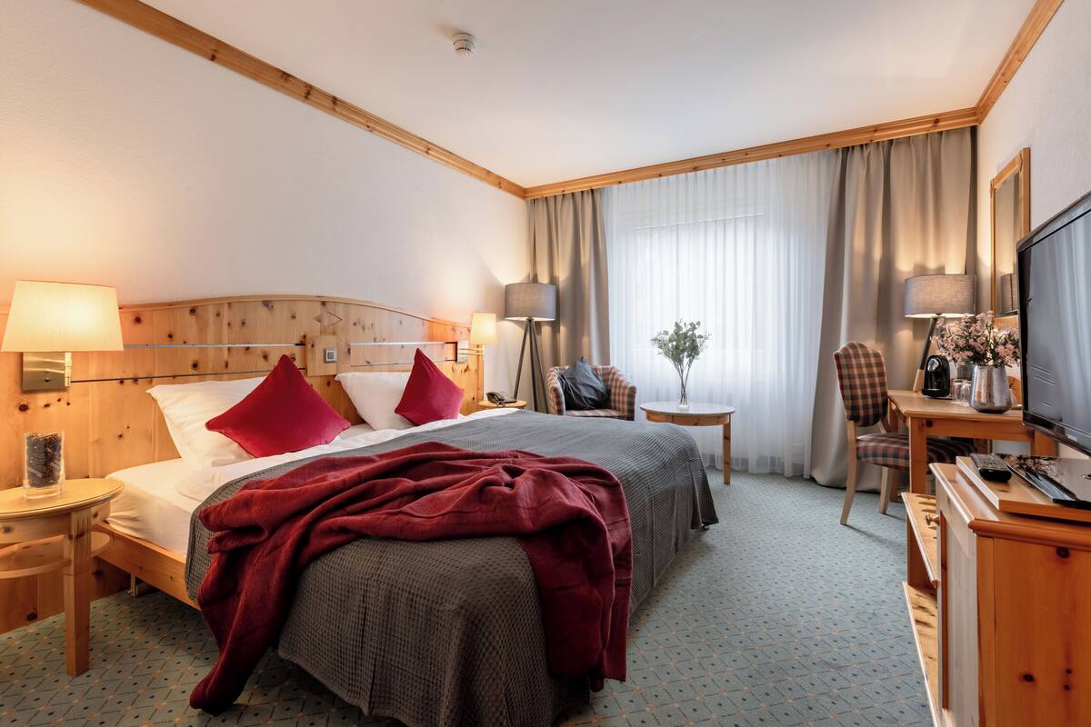 Habitació d'hotel amb dos llits, un escriptori, una cadira, una televisió i una làmpada.