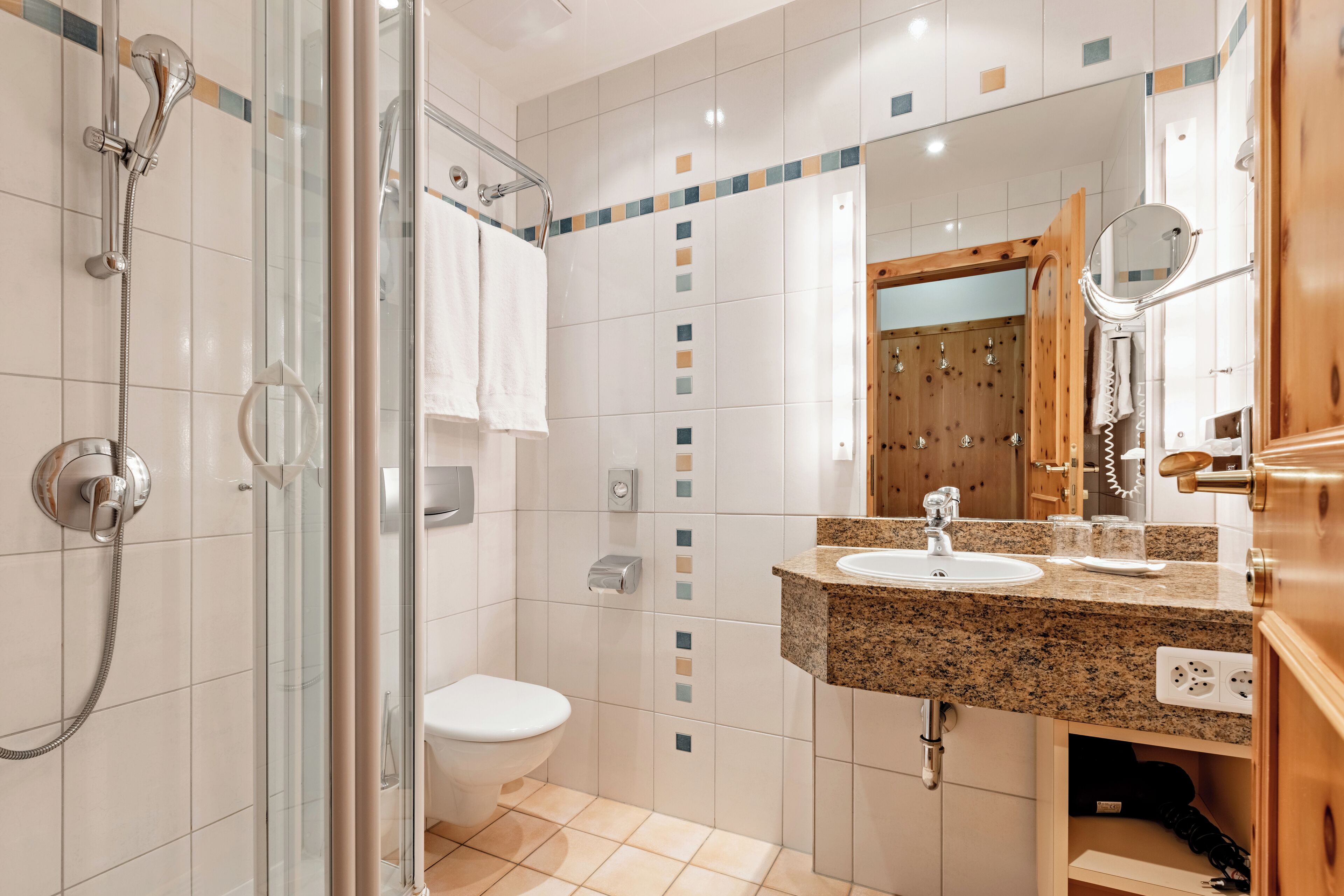 Un bagno moderno con doccia vetrata, un water bianco e un lavabo su piano in granito.
