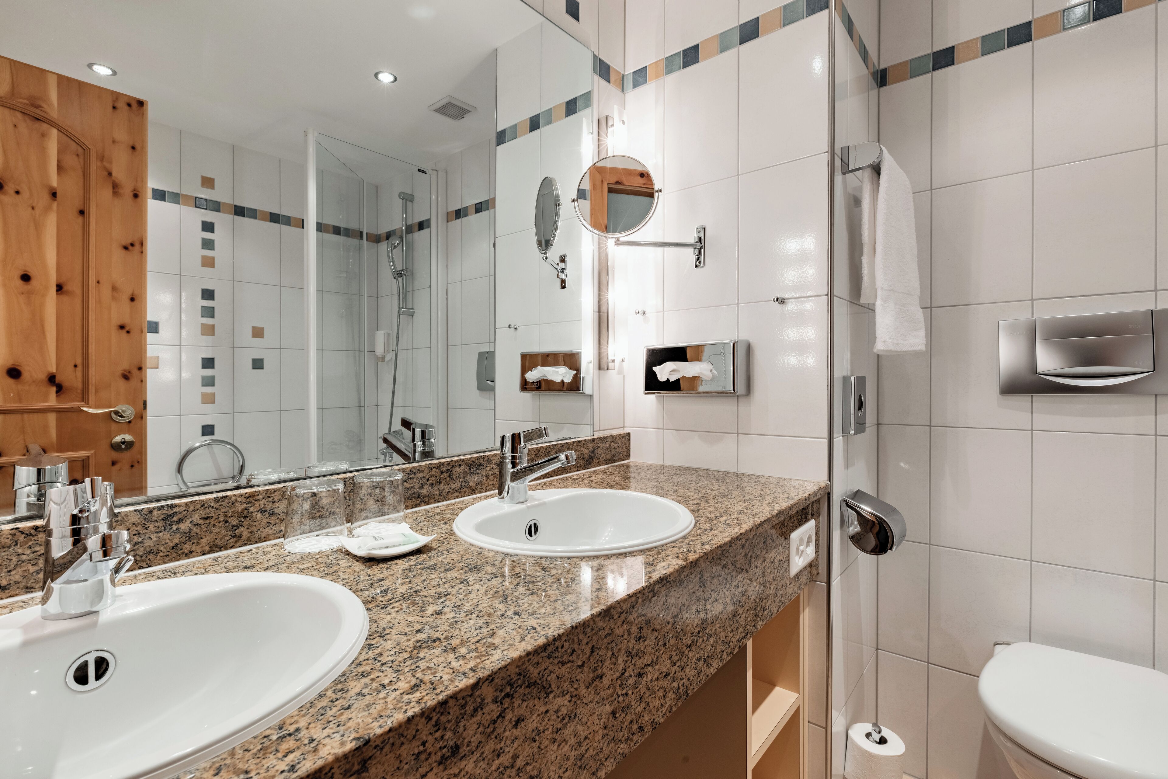 A modern bathroom with two sinks, a mirror, and a shower.