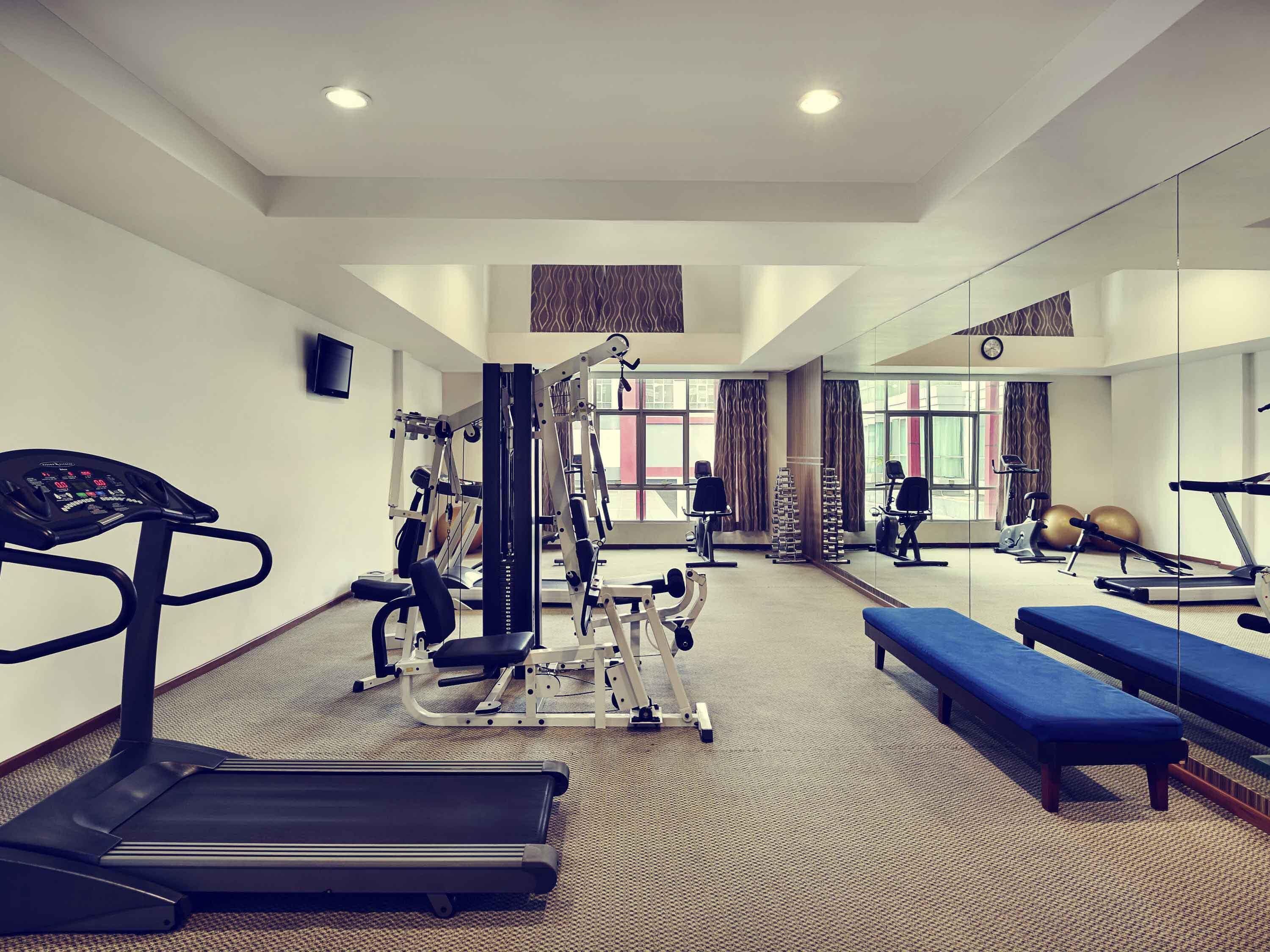 A gym with cardio equipment, weight machines, and benches.