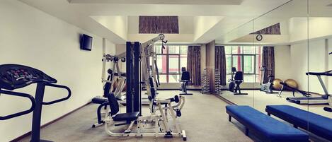 A gym with cardio equipment, weight machines, and benches.