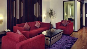 Un salon moderne avec un ensemble de canapés rouges, une table basse et un panneau décoratif mural.