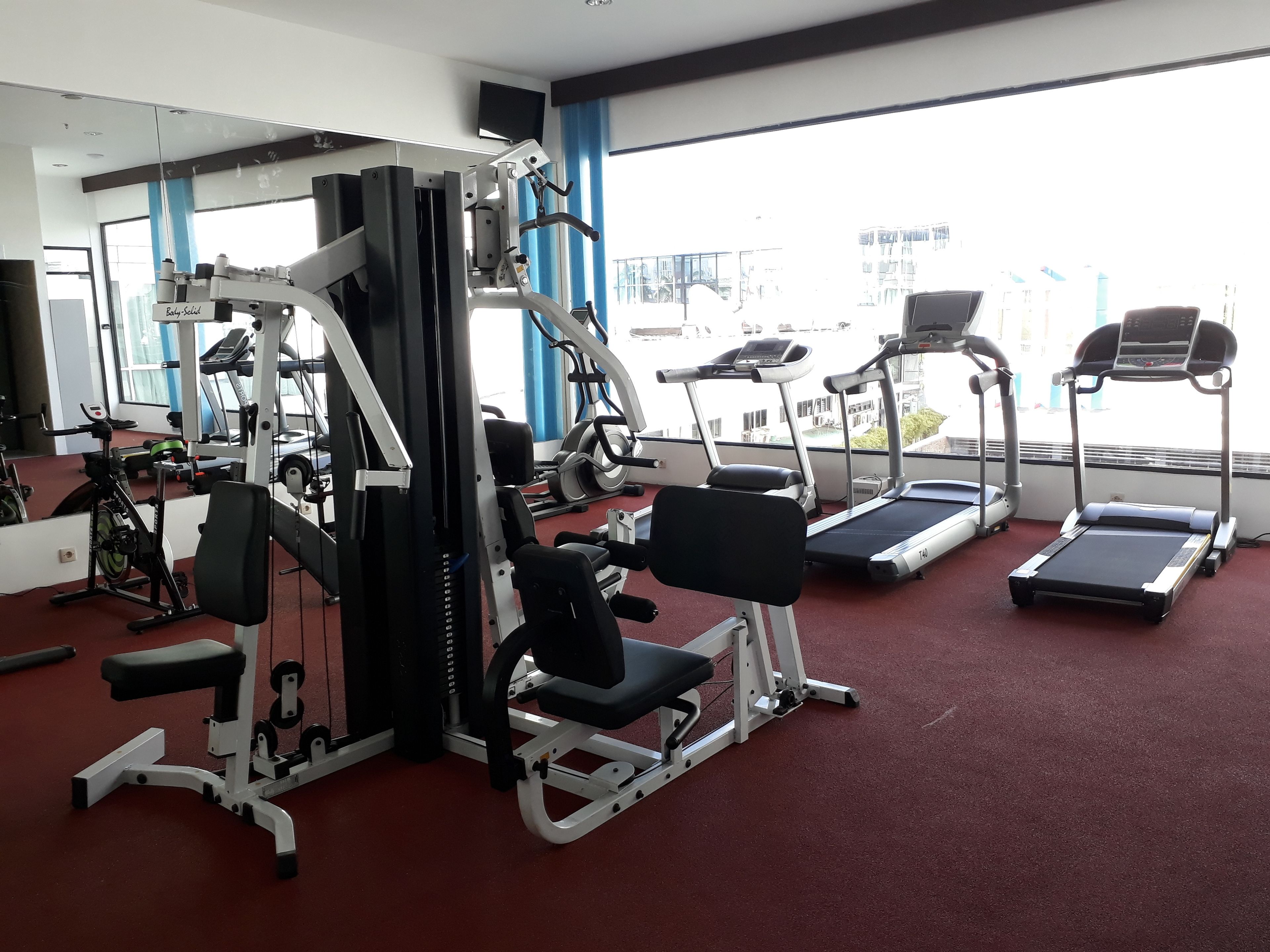 A gym with cardio machines, weight machines, and a mirrored wall.