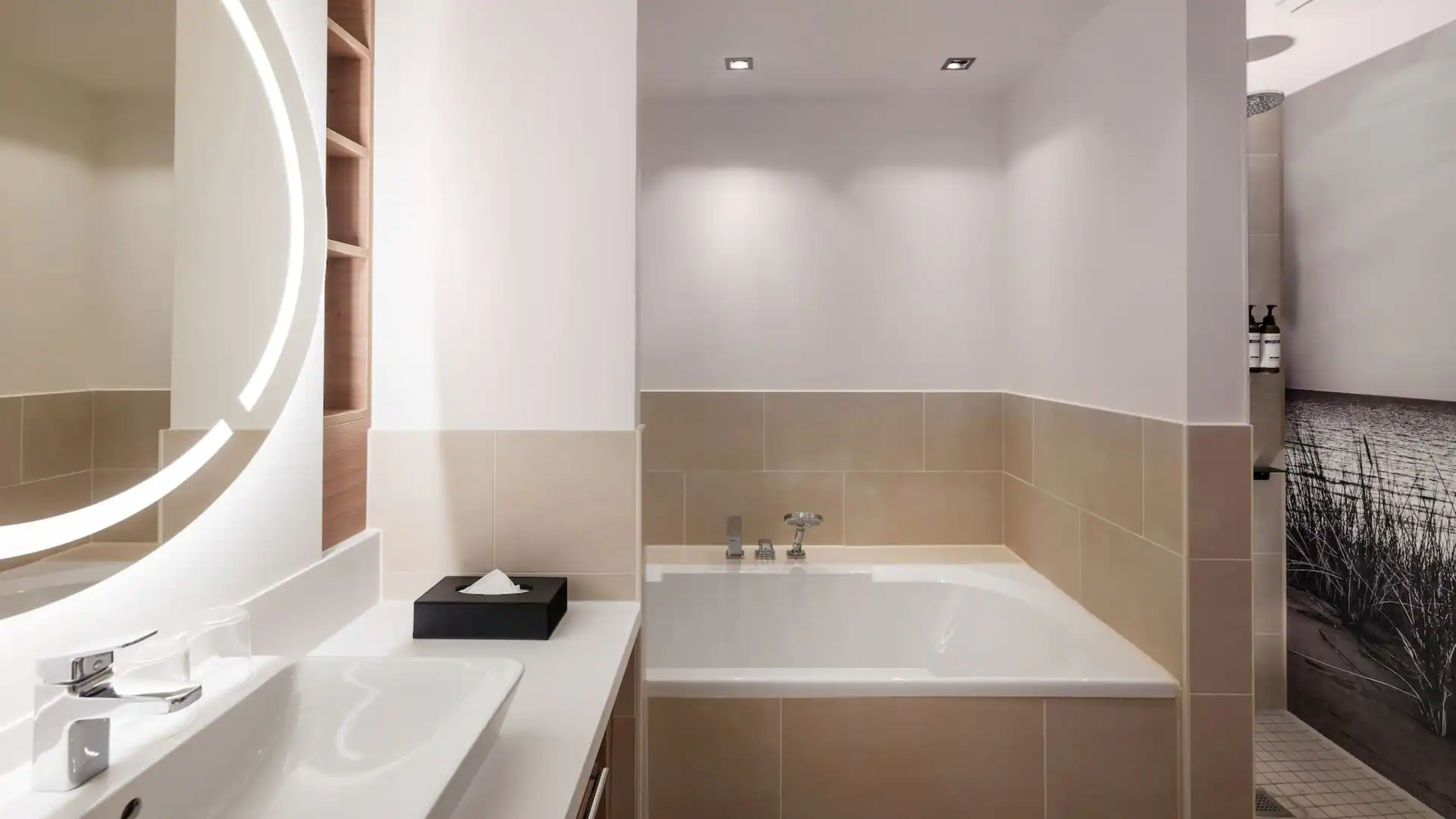 A modern bathroom with a bathtub, a large mirror, and a vanity with a sink.