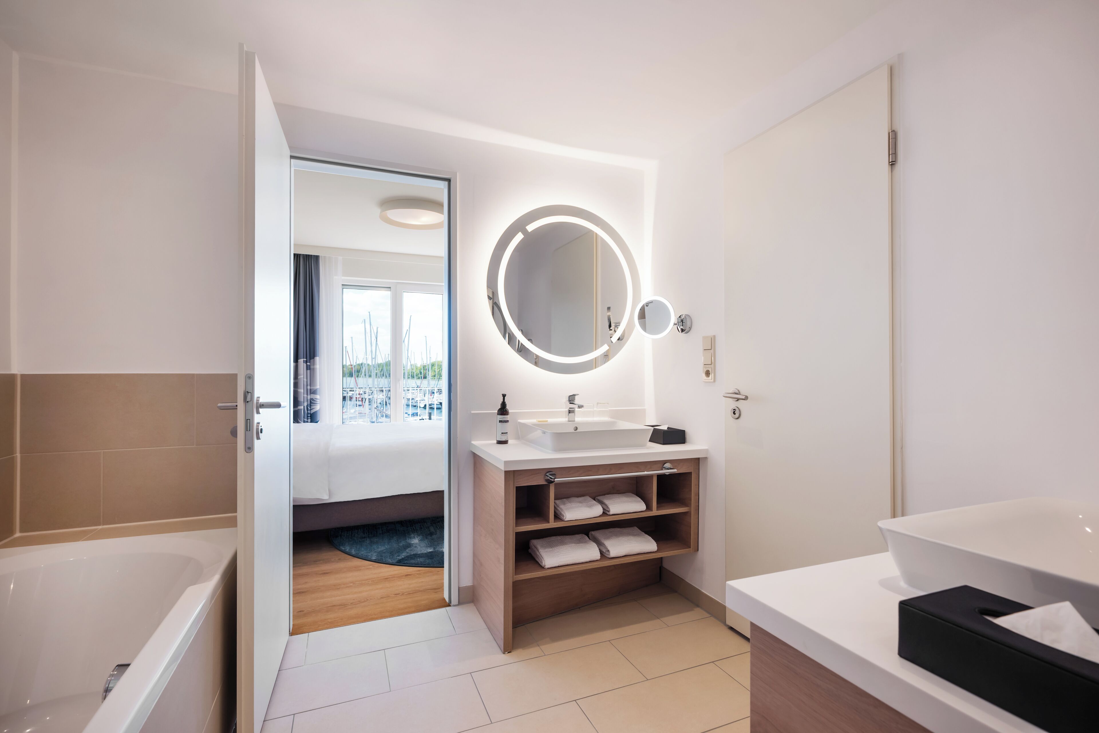 Un baño moderno con una bañera grande, un tocador con espejo y una zona separada para el lavabo.