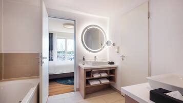 Un baño moderno con una bañera grande, un tocador con espejo y una zona separada para el lavabo.