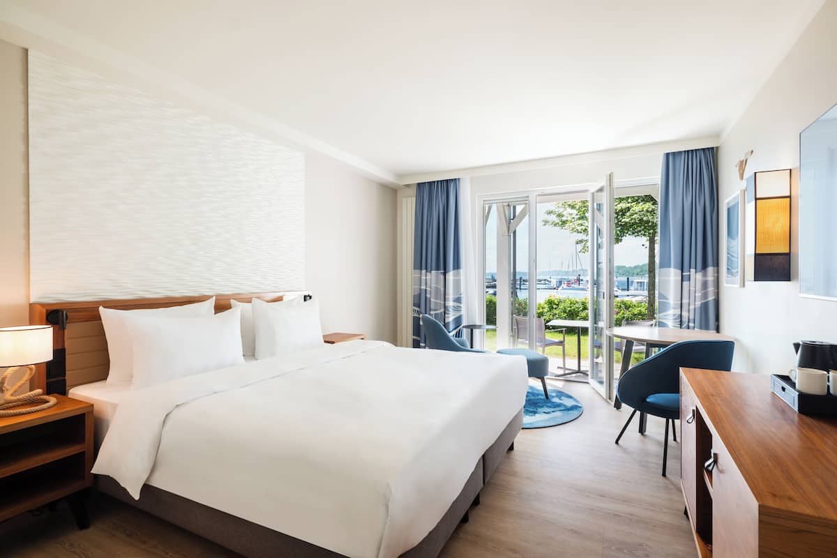 A hotel room with a large bed, a desk, and a view of the outdoors.
