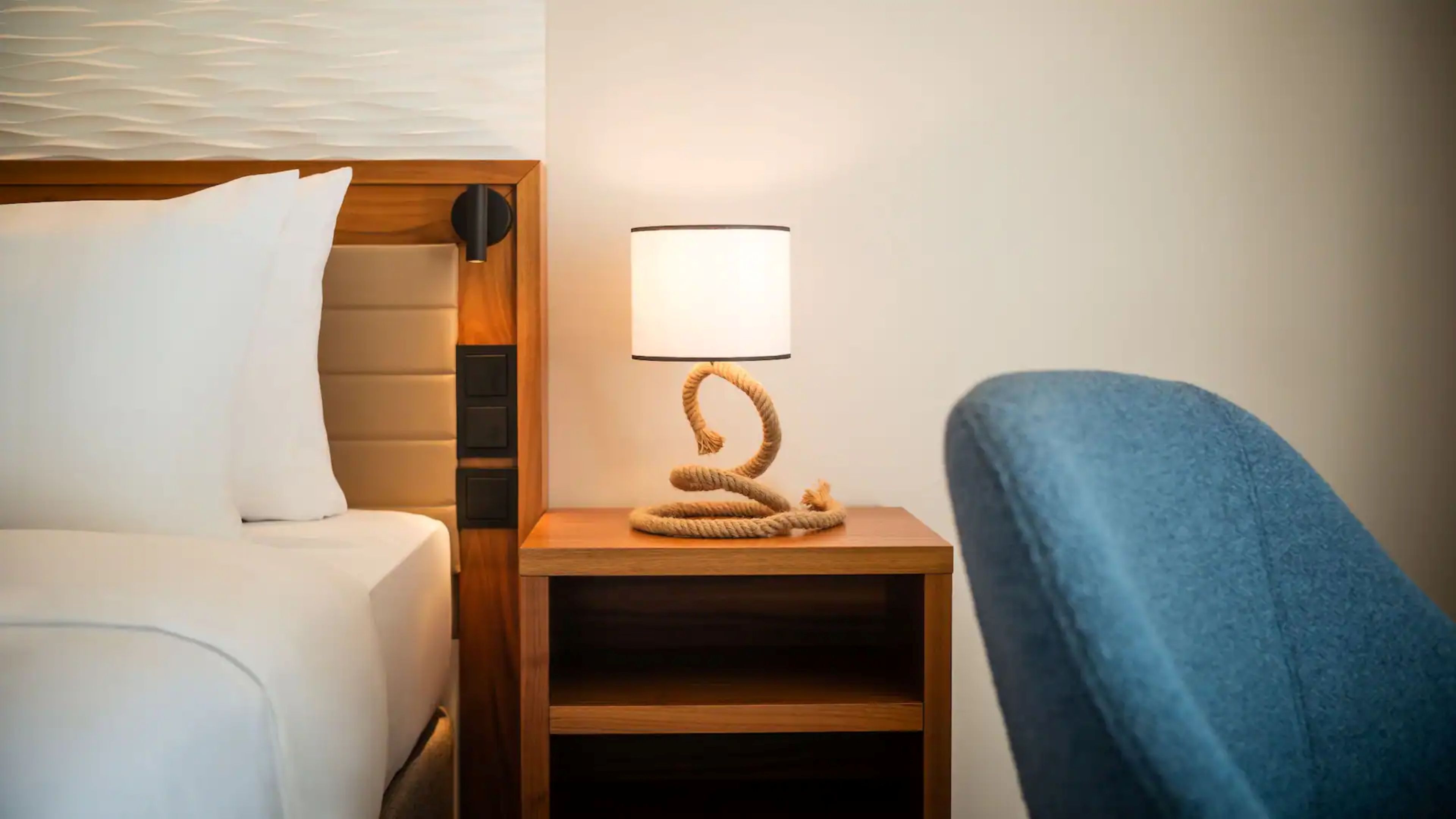 Une chambre d’hôtel avec un lit, une table de chevet avec une lampe et une chaise.