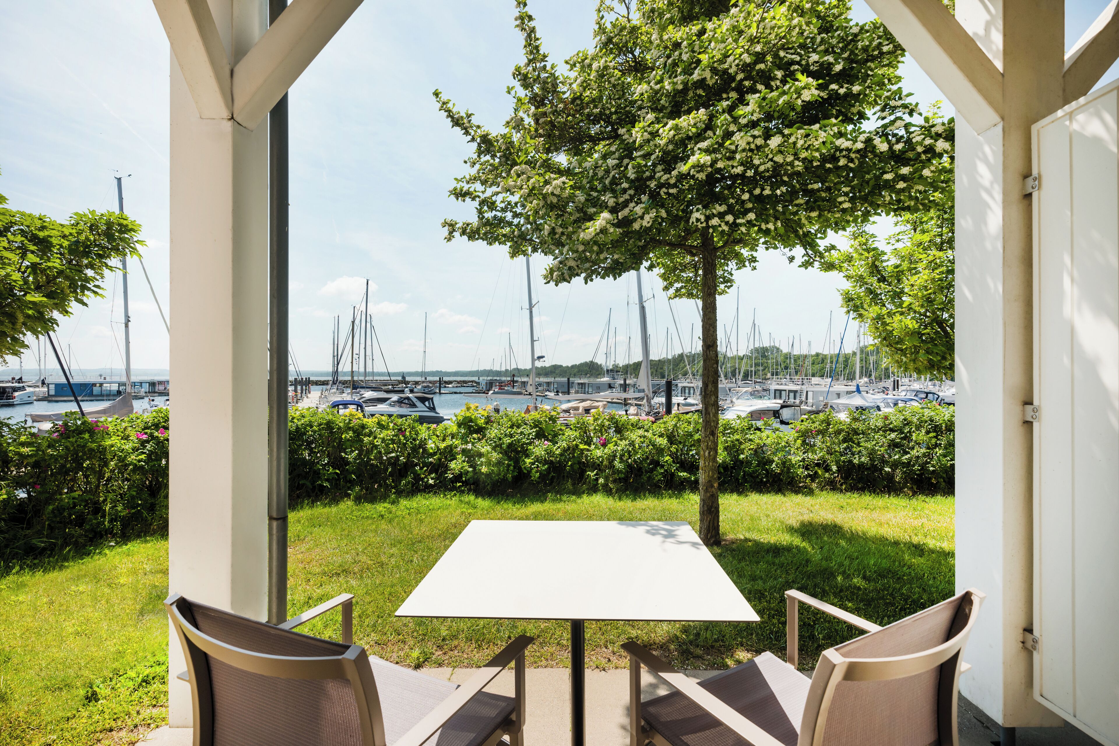 A patio with a table and chairs, overlooking a marina with boats.