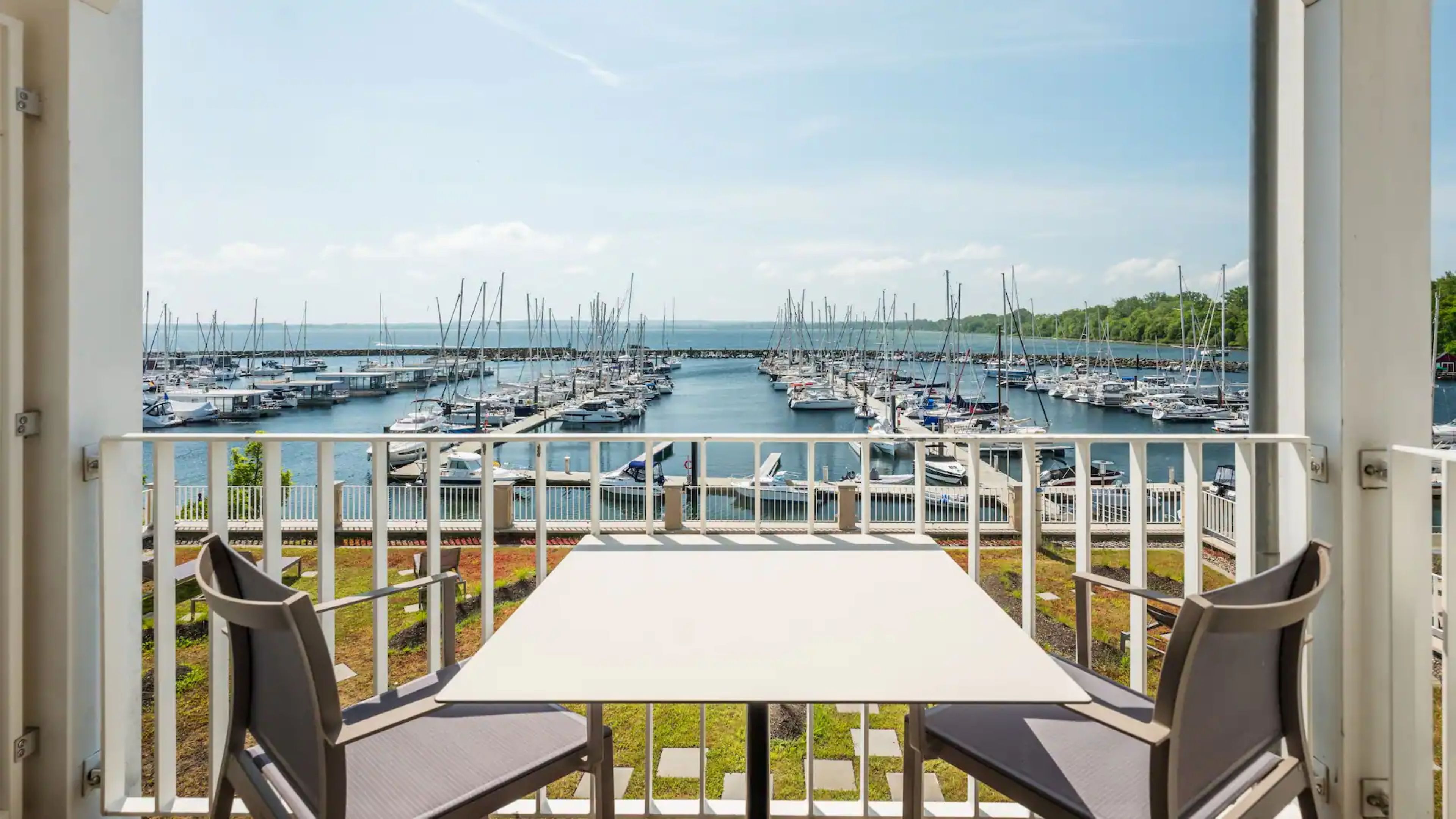 Ein Balkon mit Tisch und Stühlen mit Blick auf einen Yachthafen und zahlreichen Booten.