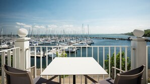 A terrace with a table and chairs overlooking a marina with numerous boats.