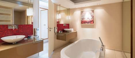 A modern bathroom with a freestanding bathtub, a large mirror, and a red-tiled wall.