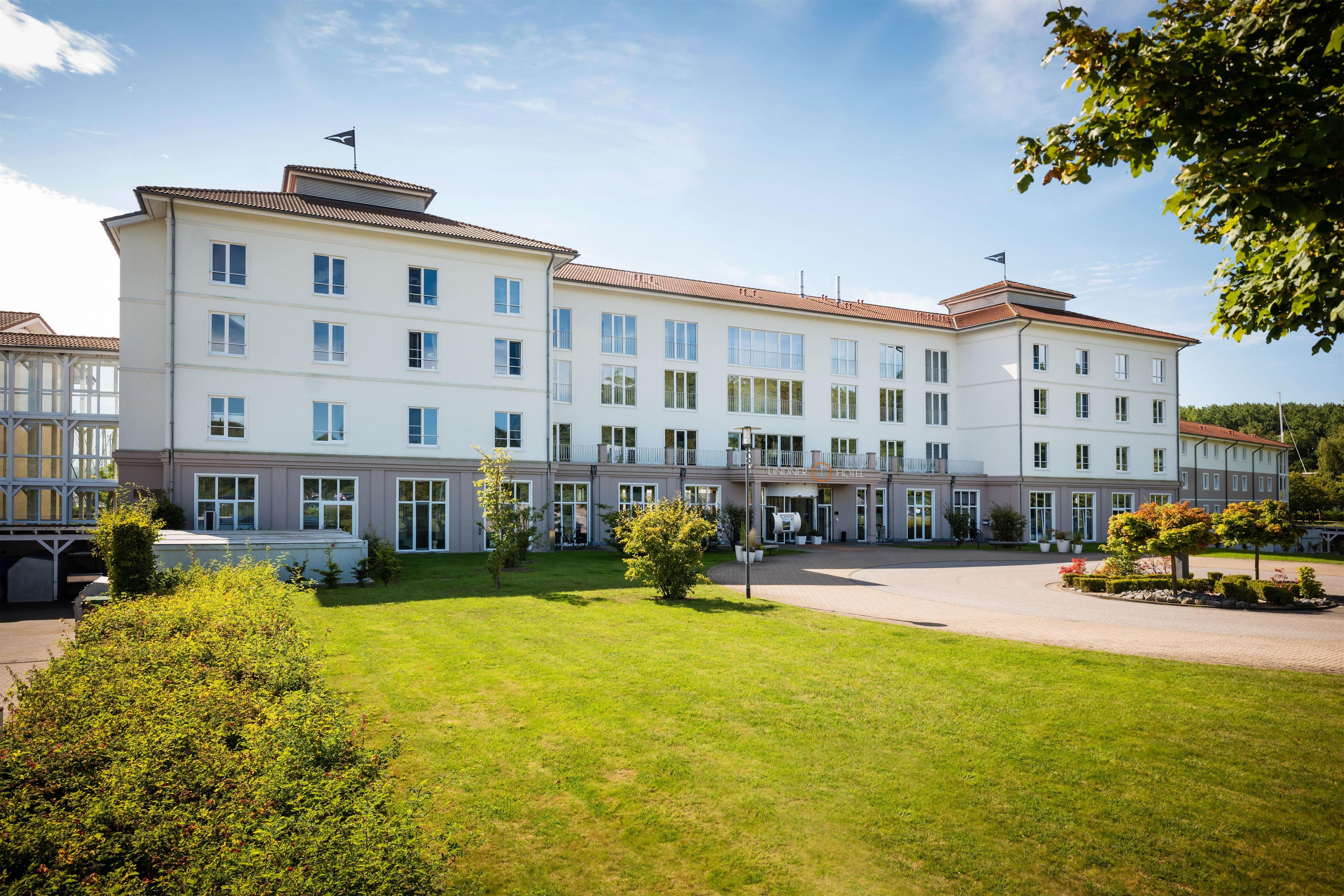 Ein mehrgeschossiges Hotel mit Innenhof, einer Flagge auf dem Dach und einem gepflegten Rasen.