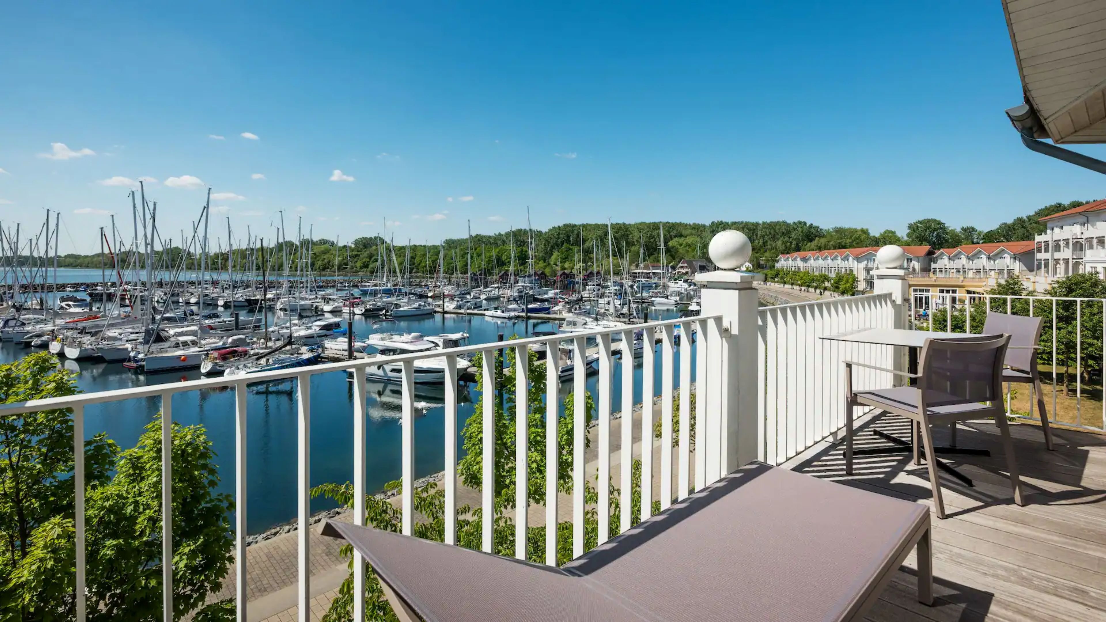Un balcon donnant sur une marina, avec des meubles d’extérieur et une balustrade blanche.