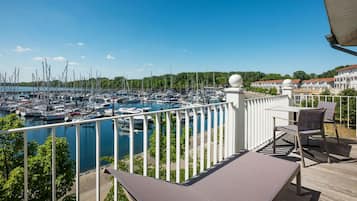 Un balcon donnant sur une marina, avec des meubles d’extérieur et une balustrade blanche.
