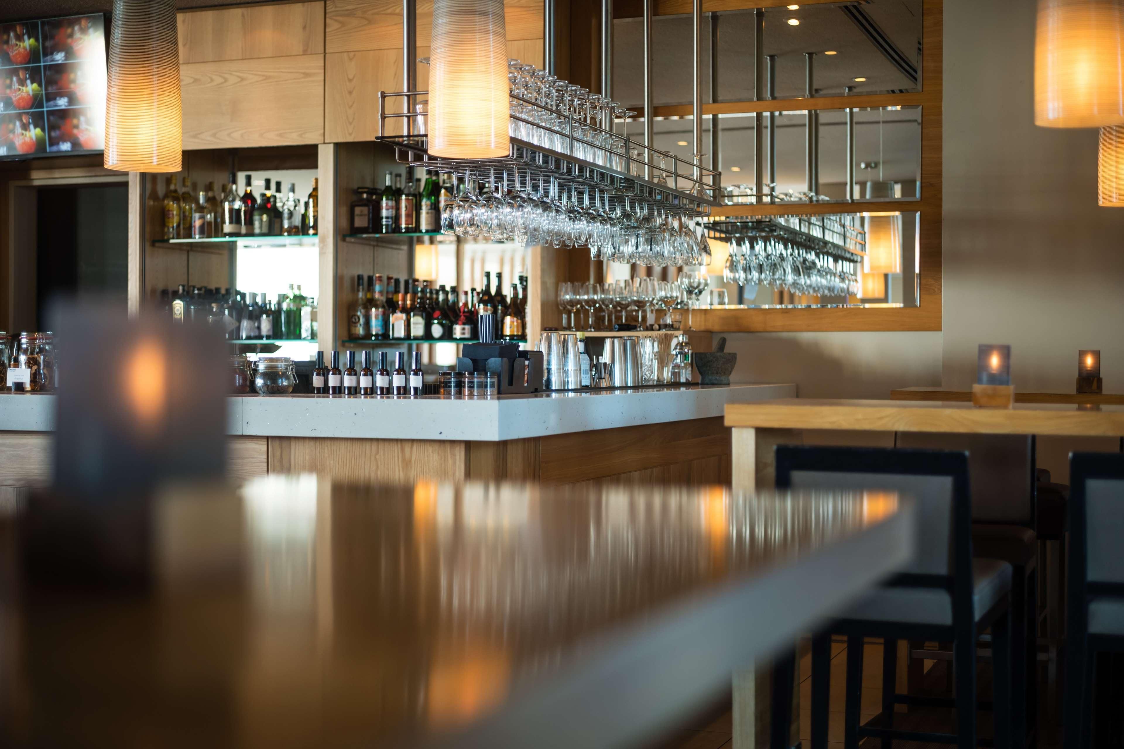 Eine Bar mit einer langen Theke, hängenden Weinflaschen und Regalen voller Flaschen.