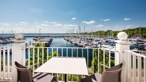 A balcony with a table and chairs overlooking a marina with numerous boats. - MAREBALTIC (Boltenhagen)